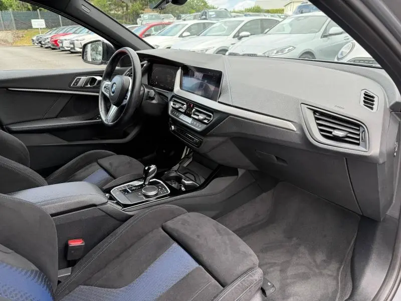 Vue intérieure côté conducteur de la BMW Série 1 118dA M Sport 2022 avec sièges sport tissu/similicuir noir et bleu.