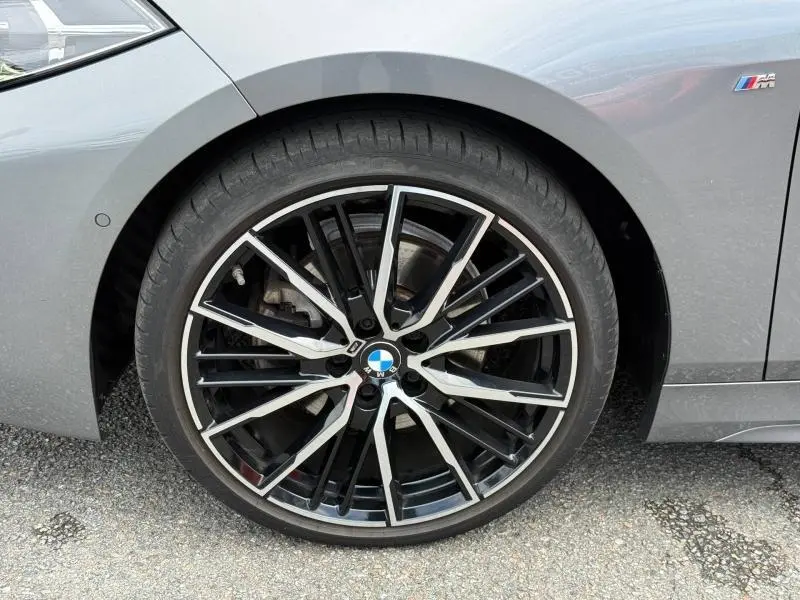 Gros plan sur la jante avant droite noire et argentée d’une BMW Série 1 118dA M Sport saphirschwarz métallisé.
