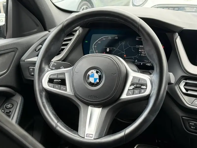 Vue rapprochée du volant cuir multifonction BMW Série 1 118dA M Sport avec tableau de bord digital et commandes intégrées.