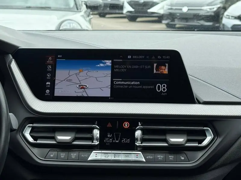 Vue intérieure du tableau de bord de la BMW Série 1 118dA 2022 avec écran tactile et commandes climatisation.