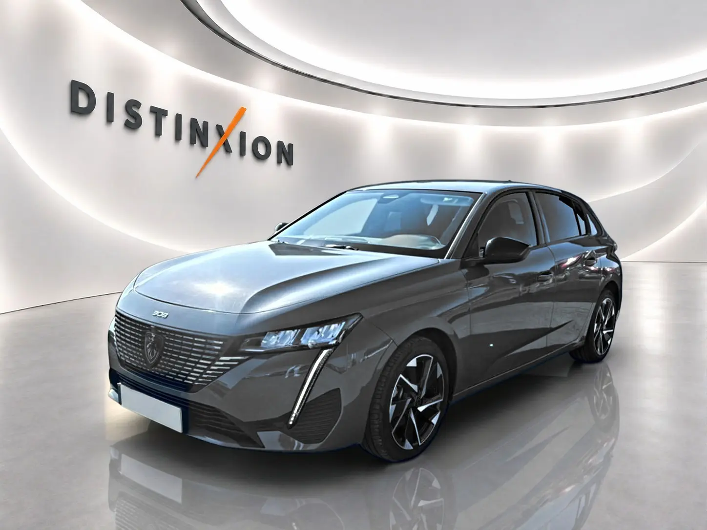 Peugeot 308 gris selenium vue 3/4 avant droit en intérieur avec éclairage moderne et jantes alu distinctives.