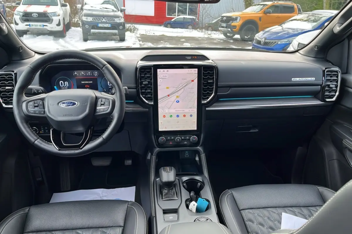 Vue intérieure avant du Ford Ranger Platinum 2026, tableau de bord noir avec écran tactile vertical et volant cuir multifonctions.