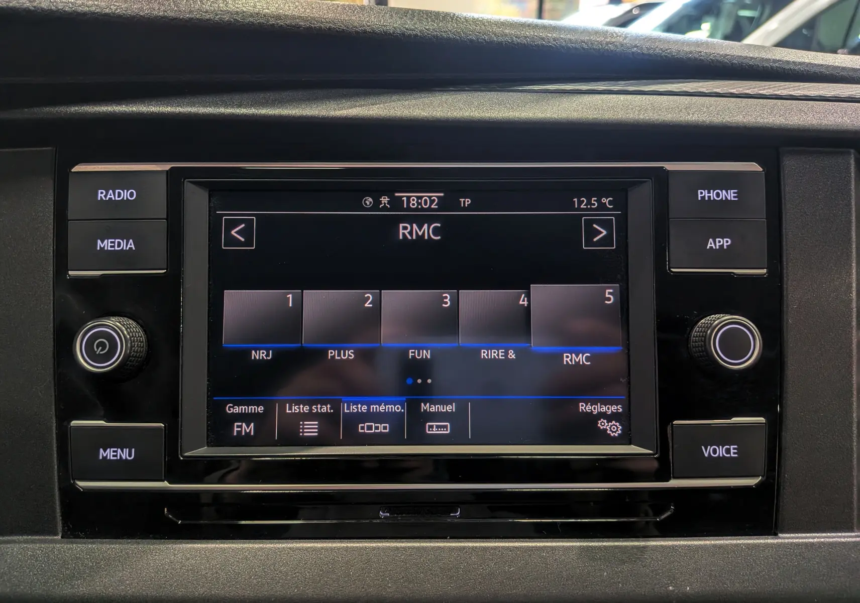 Écran tactile central du Volkswagen Transporter 6.1 blanc, affichant les options radio FM avec boutons autour en vue frontale.