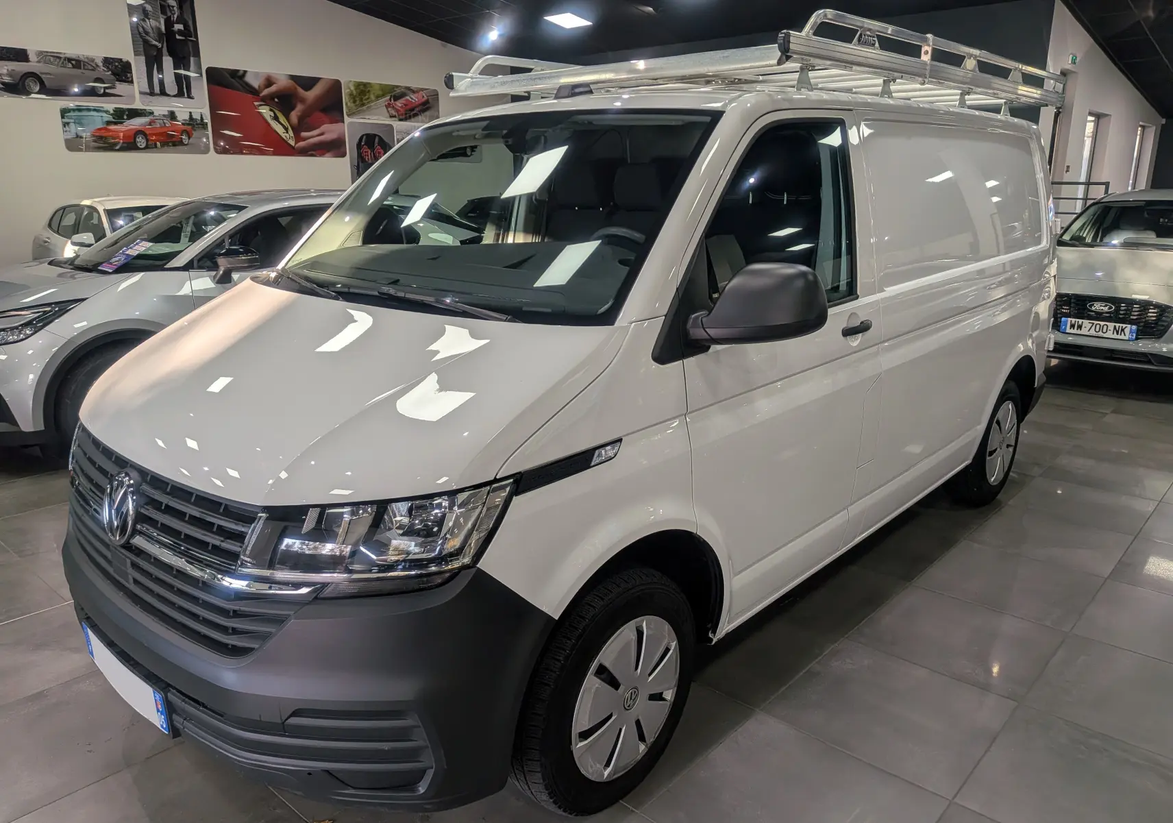 Volkswagen Transporter 6.1 blanc Candy en 3/4 avant droit avec galerie de toit en intérieur showroom.
