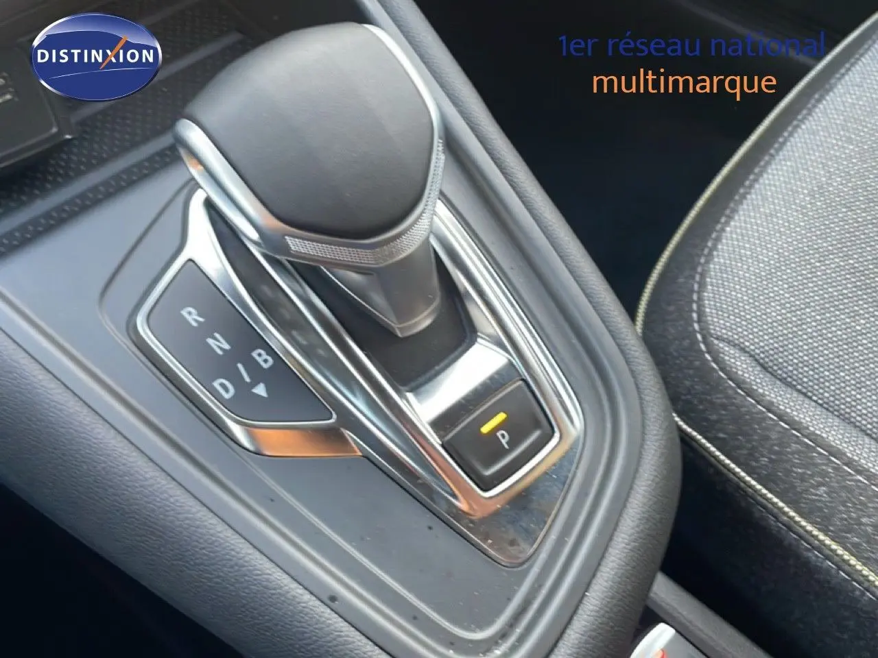 Le levier de vitesses automatique noir et chrome de la Renault Symbioz E-Tech hybride, avec siège tissu gris à côté.