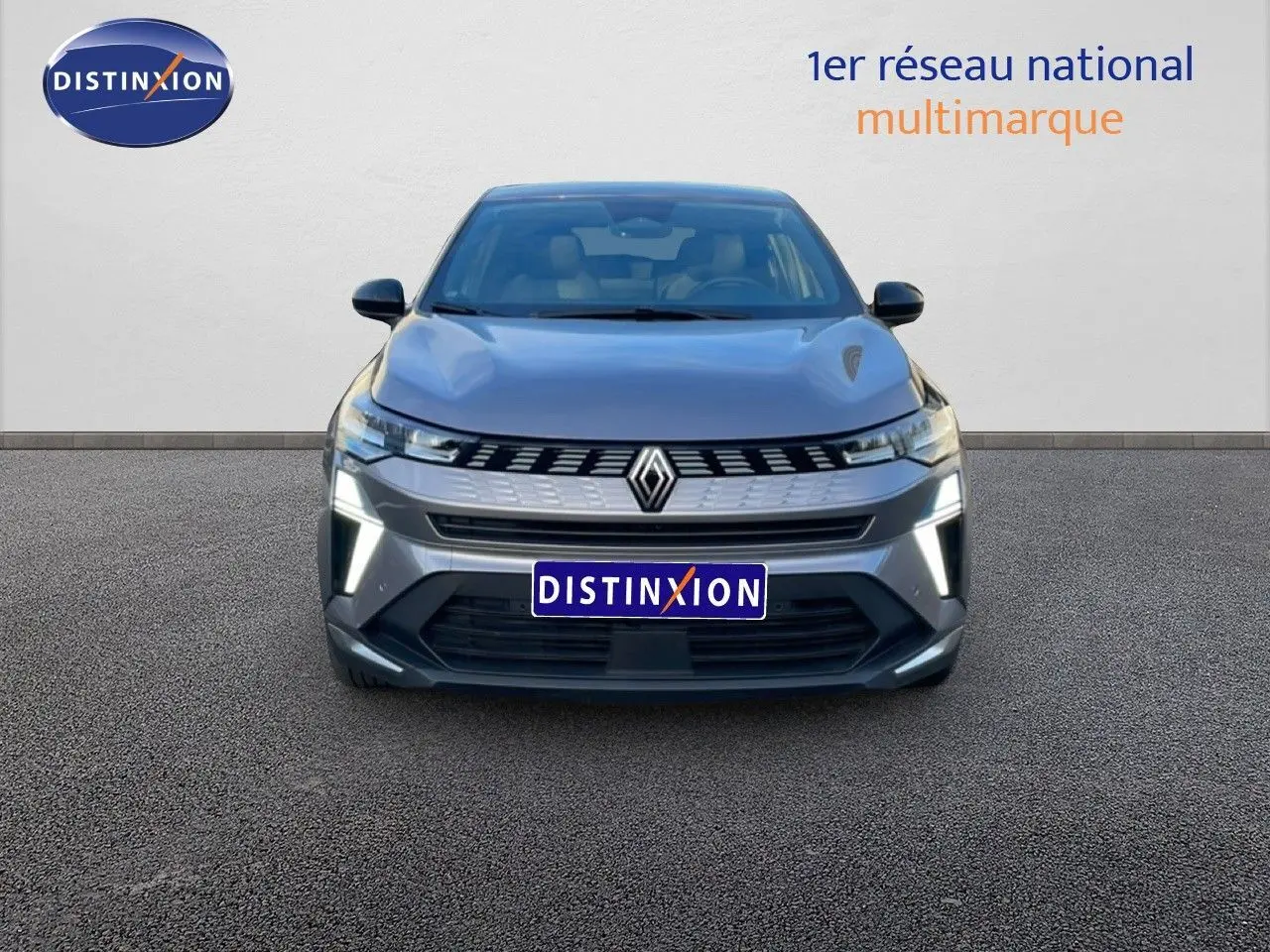 Vue frontale d'une Renault SYMBIOZ E-TECH hybride gris cassiopée métal avec feux LED allumés sur fond neutre.