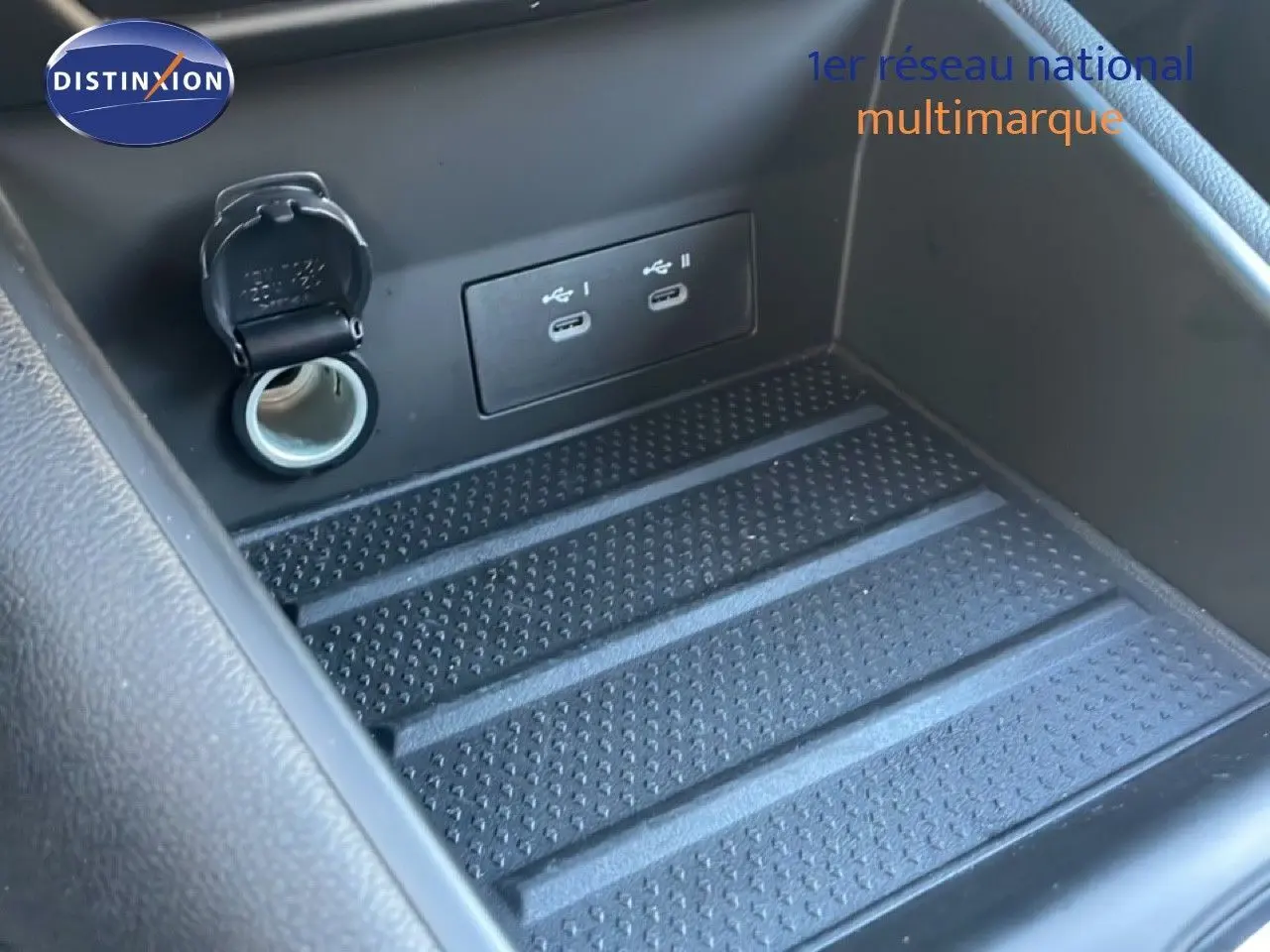 Gros plan sur la console centrale du Renault Symbioz 2025, montrant les ports USB et prise 12V dans un compartiment noir.