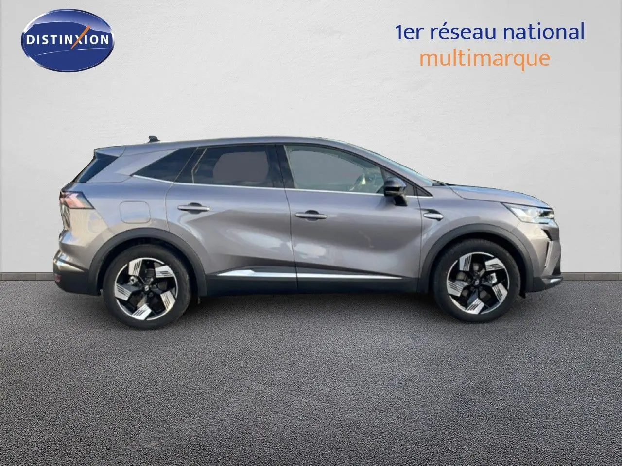 Profil droit du Renault Symbioz E-Tech hybride gris cassiopée métallisé avec jantes noires et argentées, en extérieur sur sol goudronné.