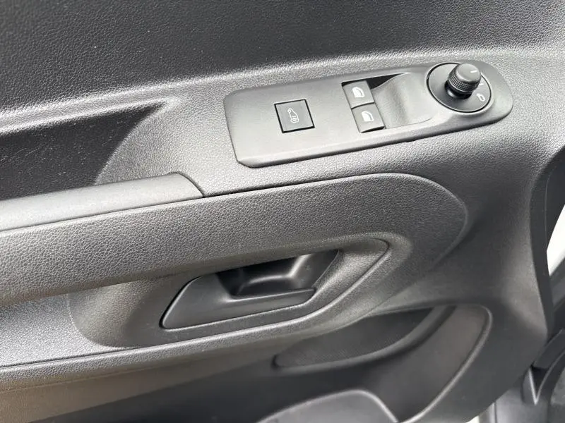 Vue rapprochée de la porte avant gauche noire du Citroën Berlingo Fourgon 2020 avec commandes électriques et poignée intégrée.