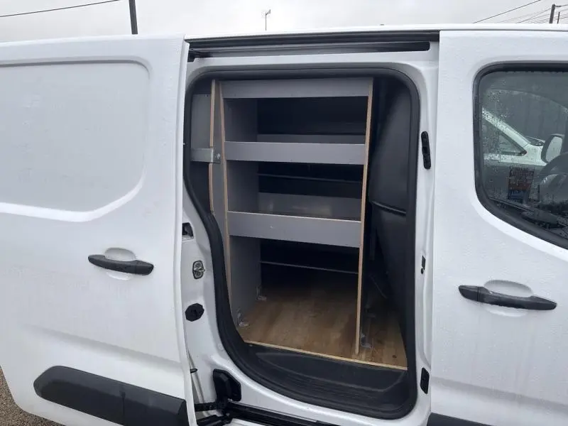 Vue latérale droite du Citroën Berlingo Fourgon blanc Banquise avec porte coulissante ouverte montrant les étagères de rangement intérieures.