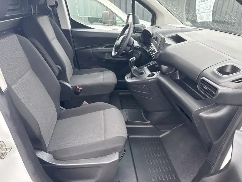 Vue intérieure côté gauche du poste de conduite du Citroën Berlingo Fourgon blanc avec sièges tissu gris et tableau de bord noir.