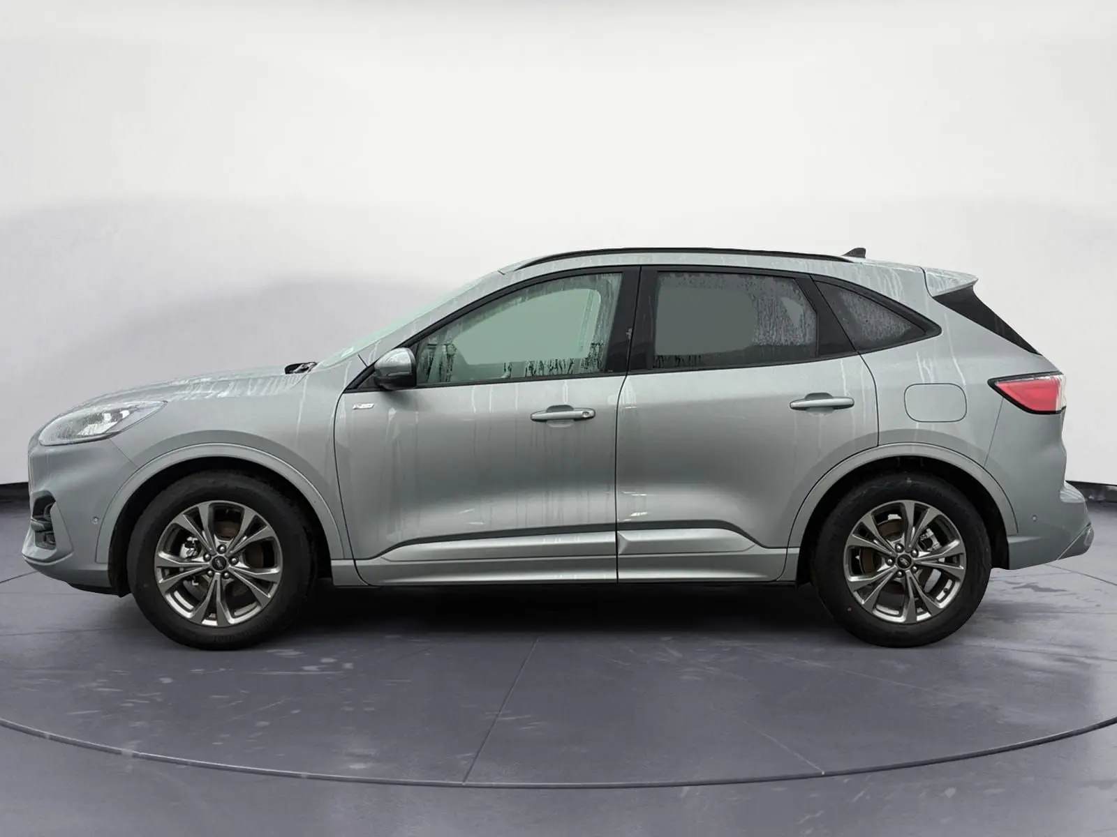 Vue latérale droite d'un Ford Kuga gris 2024, version hybride ST-Line X avec jantes alliage distinctives.