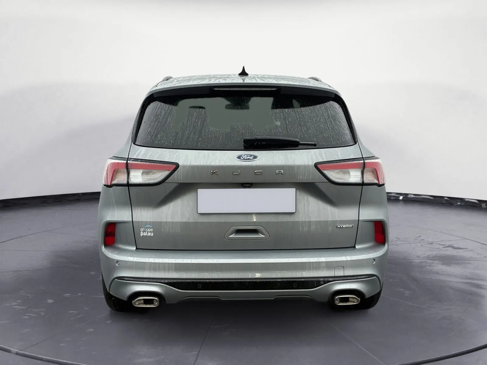 Vue arrière d'un Ford Kuga gris 2024 hybride avec double sortie d'échappement et logo KUGA bien visible.