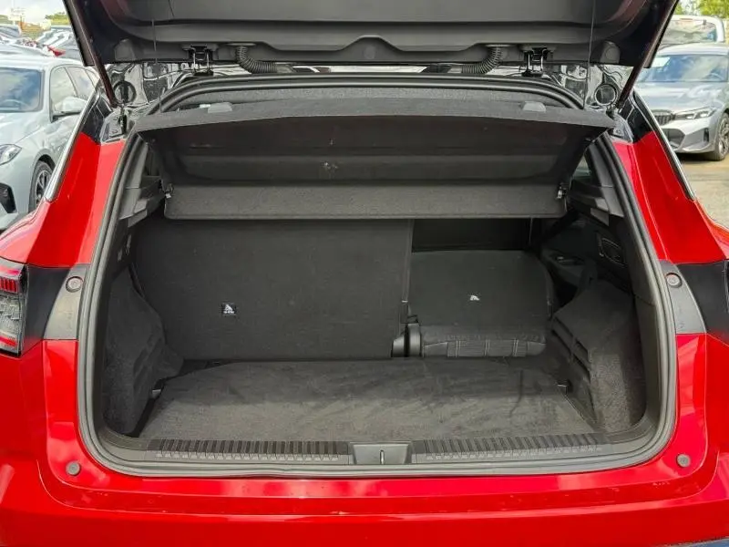 Coffre ouvert vu de l'arrière d'un Renault Austral 2025 Rouge Flamme avec banquette partiellement rabattue.