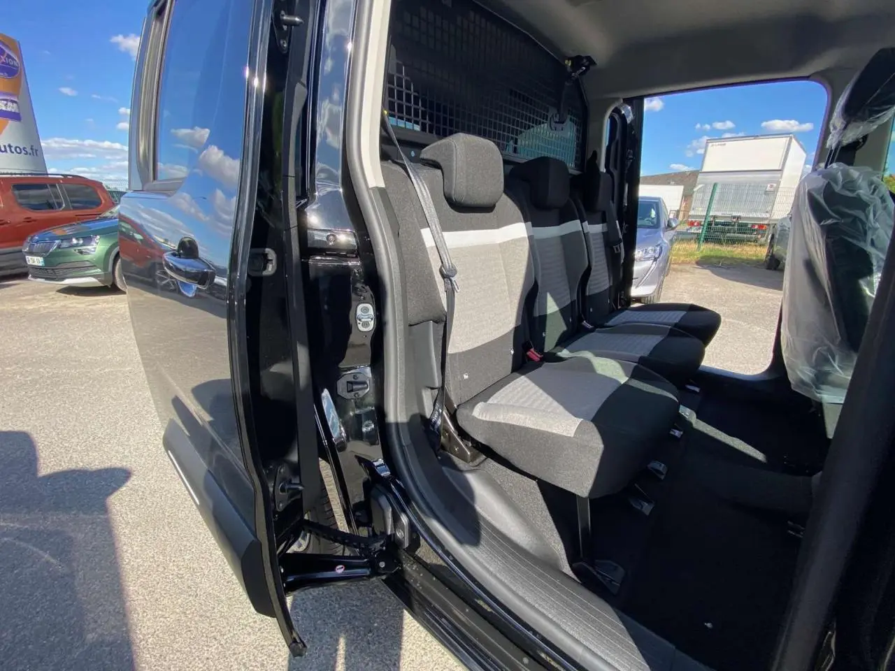 Vue intérieure côté gauche du Citroën Berlingo noir 2026, montrant les sièges arrière et la porte coulissante ouverte.