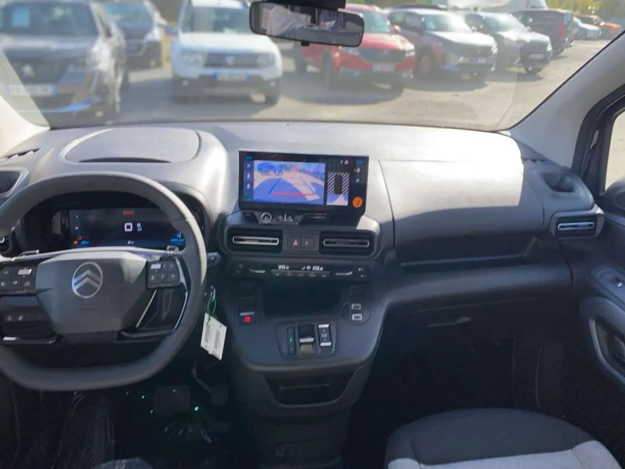 Vue intérieure avant du Citroën Berlingo noir 2026, tableau de bord avec écran caméra de recul et volant multifonction.