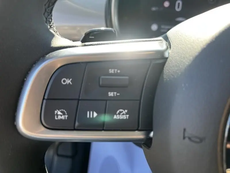 Gros plan sur les commandes au volant côté gauche du Fiat 600 T-Gen 3 beige, avec boutons de régulateur et assistances visibles.