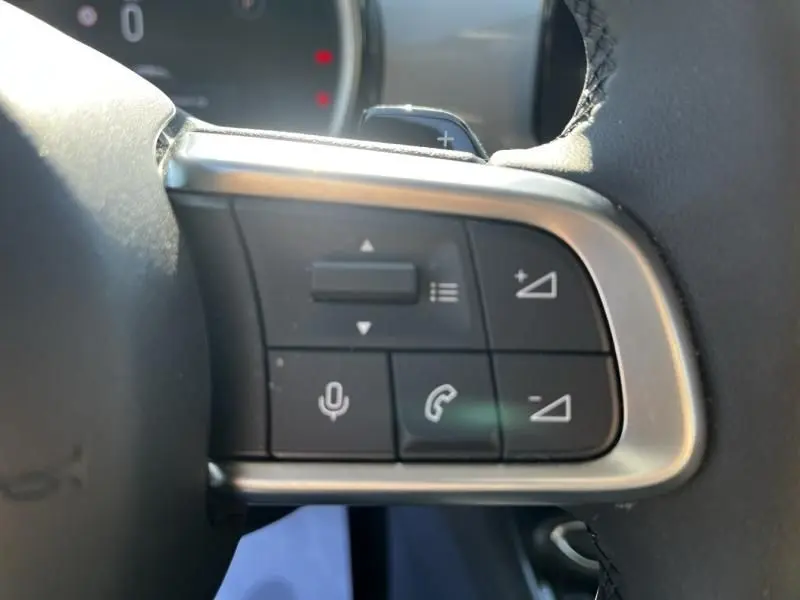 Gros plan sur les commandes au volant côté droit du Fiat 600 T-Gen 3 beige, avec boutons de volume, appel et commande vocale.