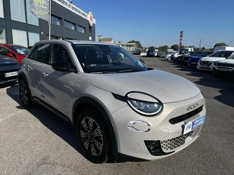 Vue 3/4 avant droite d'une FIAT 600 T-Gen 3 beige 2025 avec phares ronds et jantes noires stylisées.