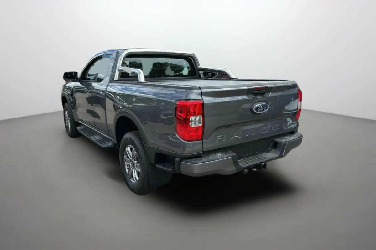 Ford Ranger gris carbone en 3/4 arrière droit avec arceaux inox et benne ouverte, vue sur hayon et feux rouges.