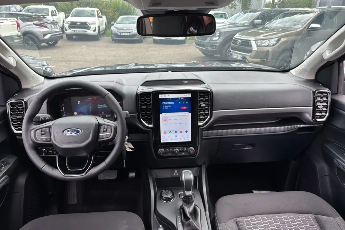 Intérieur du Ford Ranger gris carbone, vue frontale du tableau de bord avec écran tactile vertical et volant multifonctions.