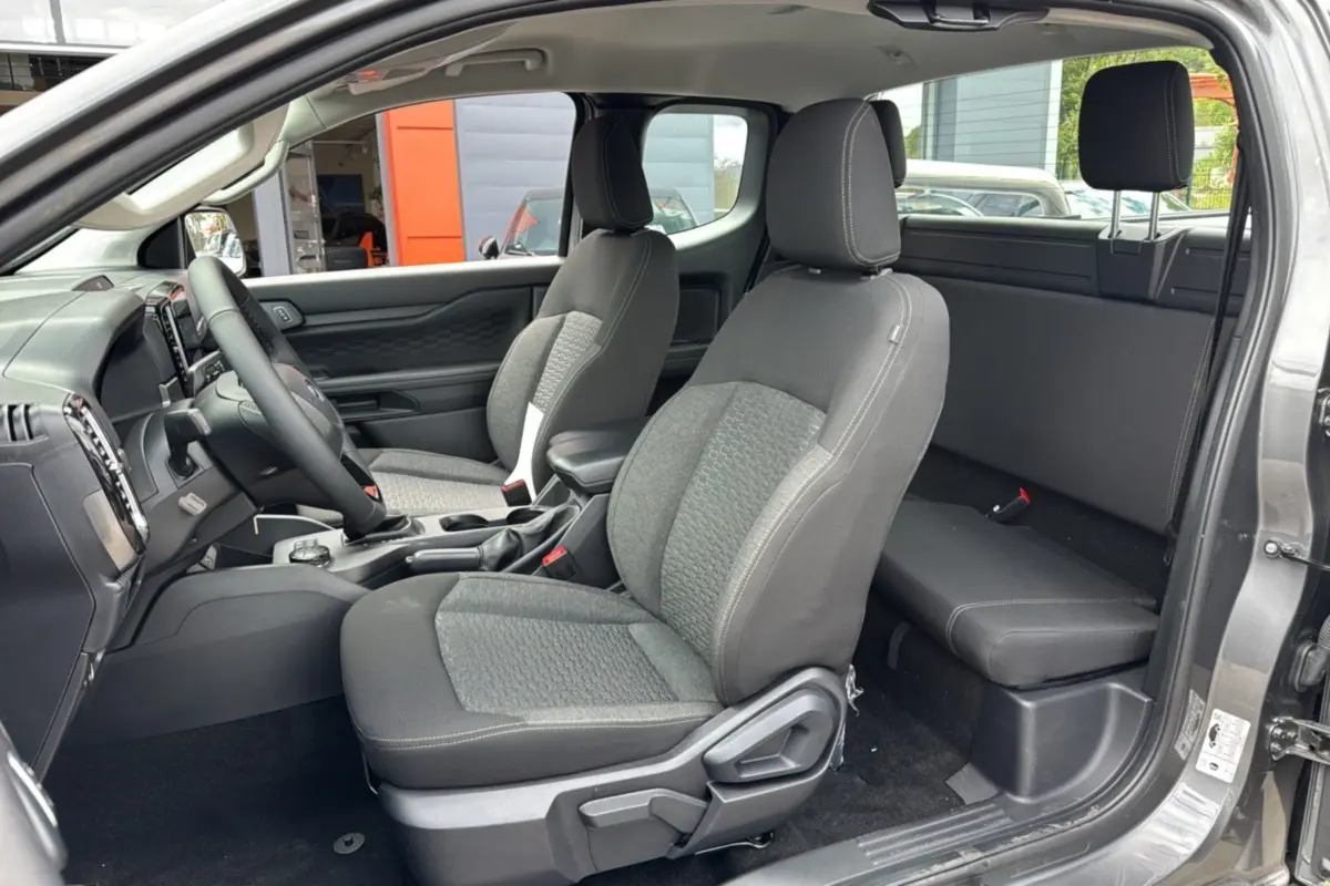 Vue intérieure côté conducteur du Ford Ranger gris carbone 2026, montrant les sièges avant et la banquette arrière compacte.