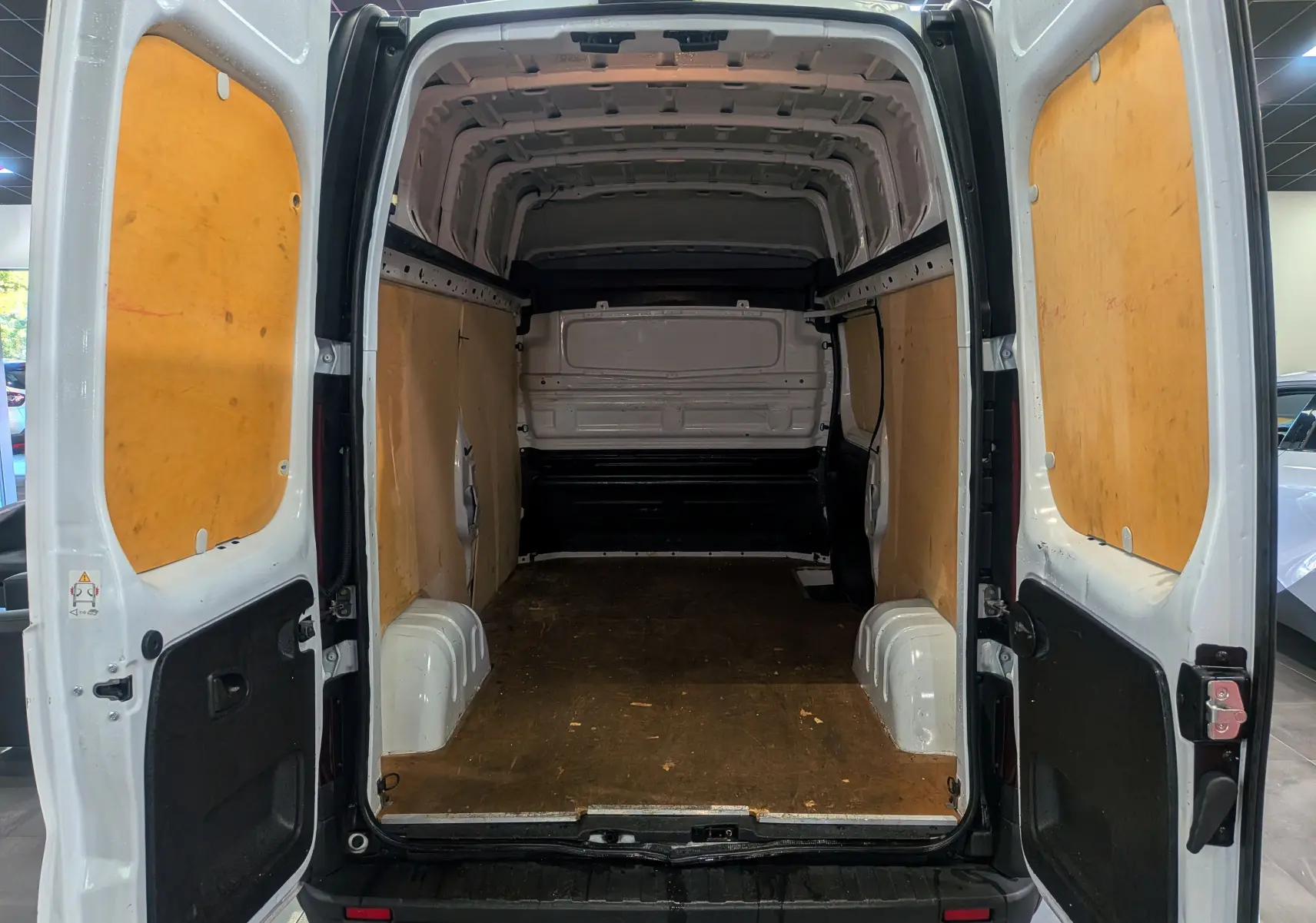 Vue arrière ouverte du Renault Trafic Fourgon blanc glacier L2H2 montrant l'espace de chargement avec parois en bois.