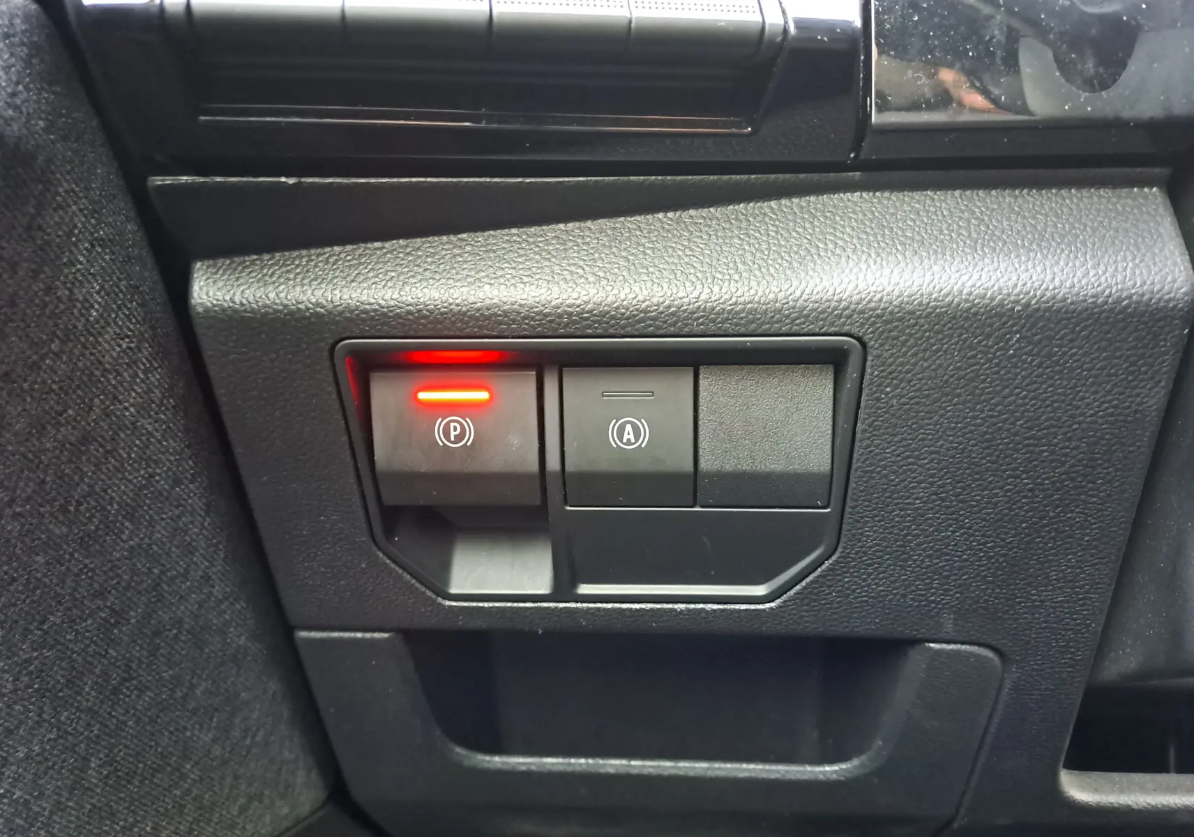 Gros plan sur les boutons du frein à main électrique et de l'arrêt automatique dans un Renault Austral gris schiste 2023.
