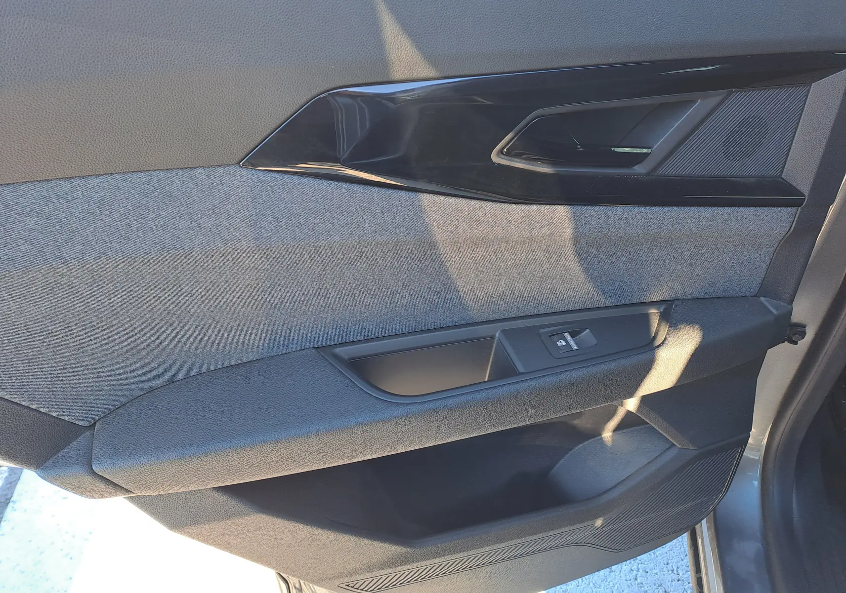 Détail de la porte intérieure côté gauche du Renault Austral gris schiste, avec habillage tissu et commande de vitre.