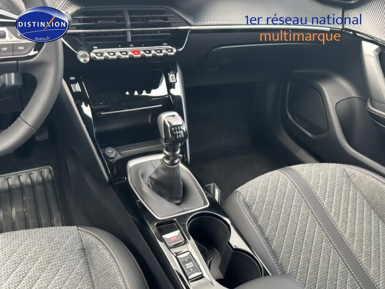 Intérieur Peugeot 2008 1.2 100 allure 2025, vue sur la console centrale avec levier de vitesse manuel et sièges tissu gris.