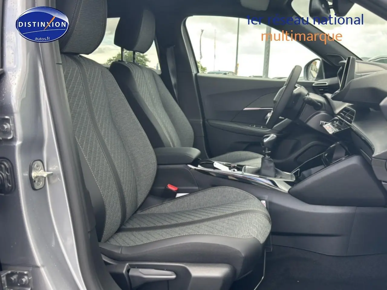 Vue intérieure côté conducteur du Peugeot 2008 gris artense 2025, montrant les sièges en tissu casual lomsa embossé et la console centrale avec boîte manuelle.