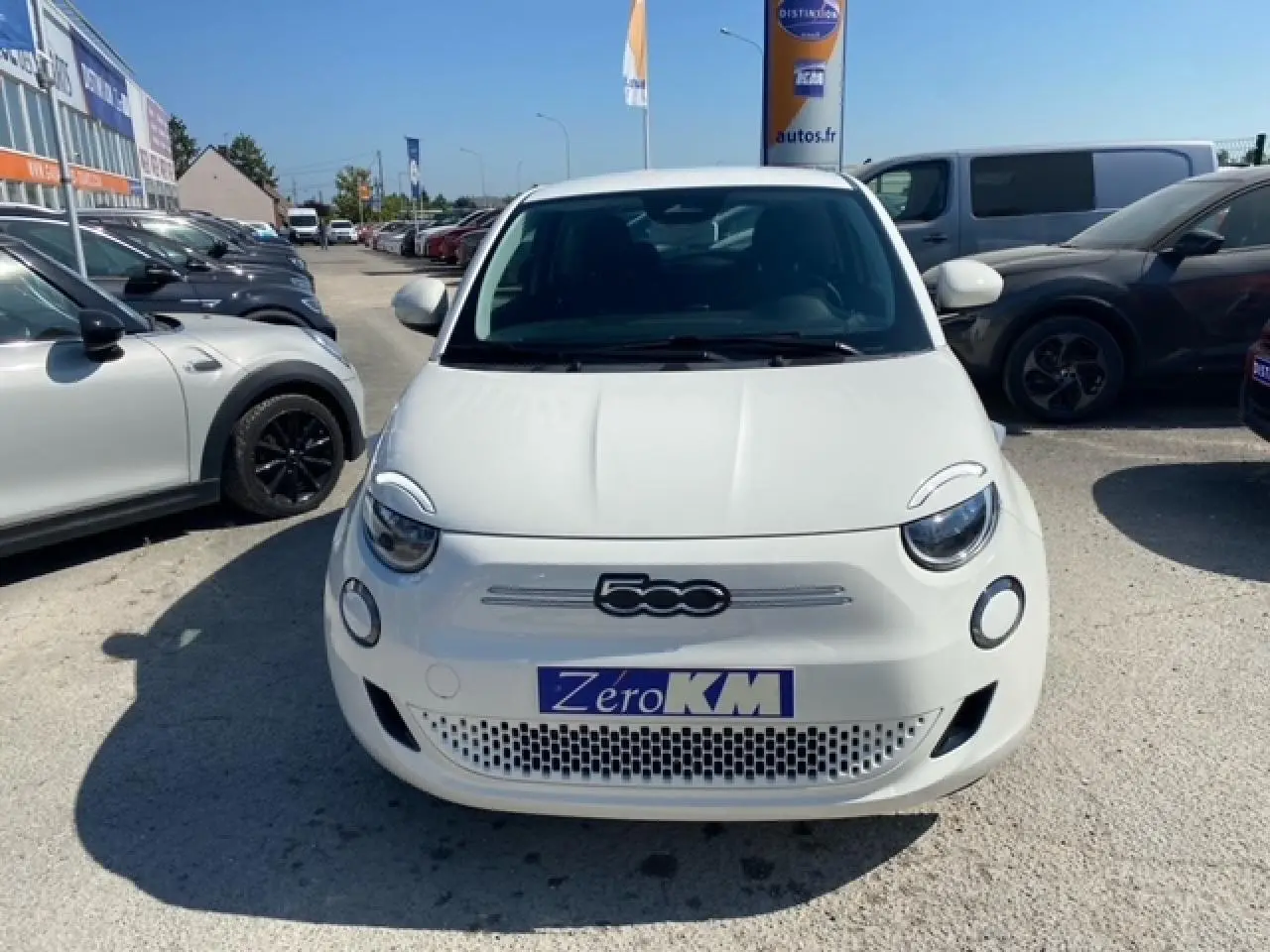 Vue de face d'une FIAT 500 électrique blanche Ice White avec logo 500 et plaque Zéro KM visible.