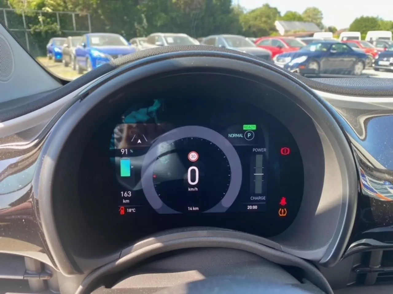 Vue rapprochée du tableau de bord numérique de la Fiat 500 électrique blanche, affichant vitesse et autonomie.