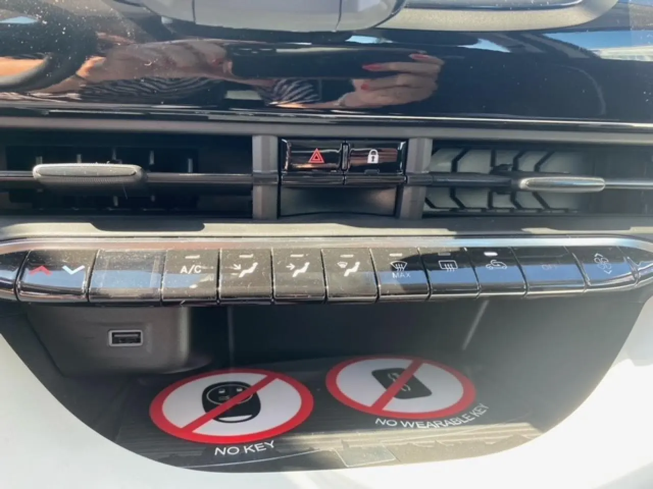 Vue rapprochée de la console centrale noire du Fiat 500 électrique blanc, avec commandes climatisation et ventilation.