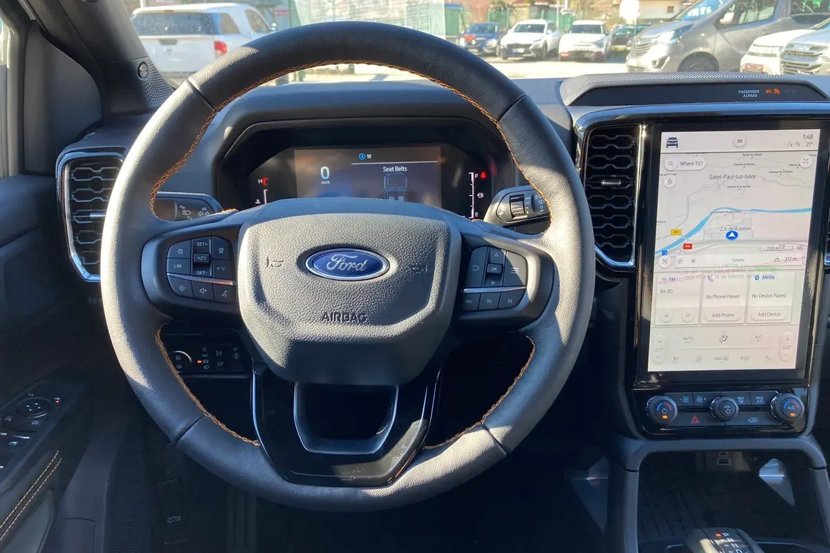 Vue intérieure centrée sur le volant cuir noir avec coutures marron et écran tactile vertical du Ford Ranger gris carbone 2026.