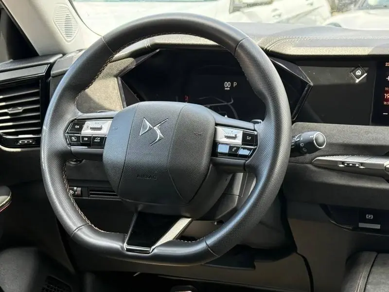 Vue rapprochée du volant cuir noir du DS4 2024 avec commandes intégrées et tableau de bord numérique.