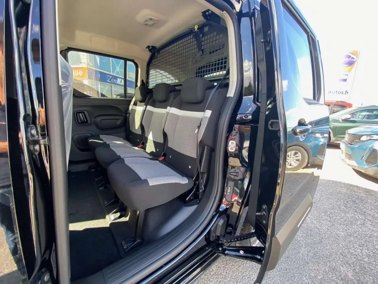 Vue latérale droite du Citroën Berlingo noir 2026, porte coulissante ouverte révélant la banquette arrière grise et noire.