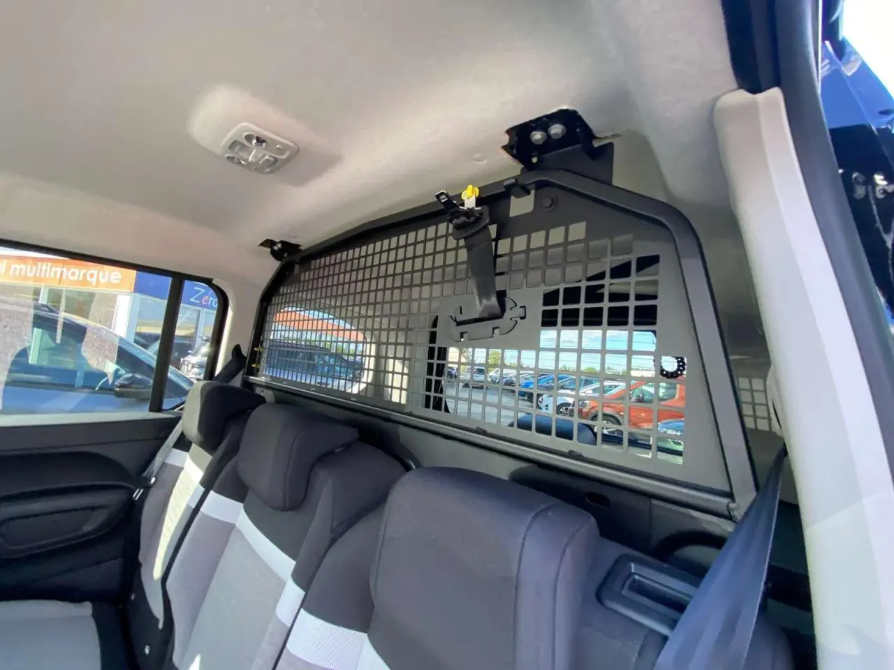 Vue intérieure arrière du Citroën Berlingo noir 2026 montrant la grille de séparation et les sièges arrière.