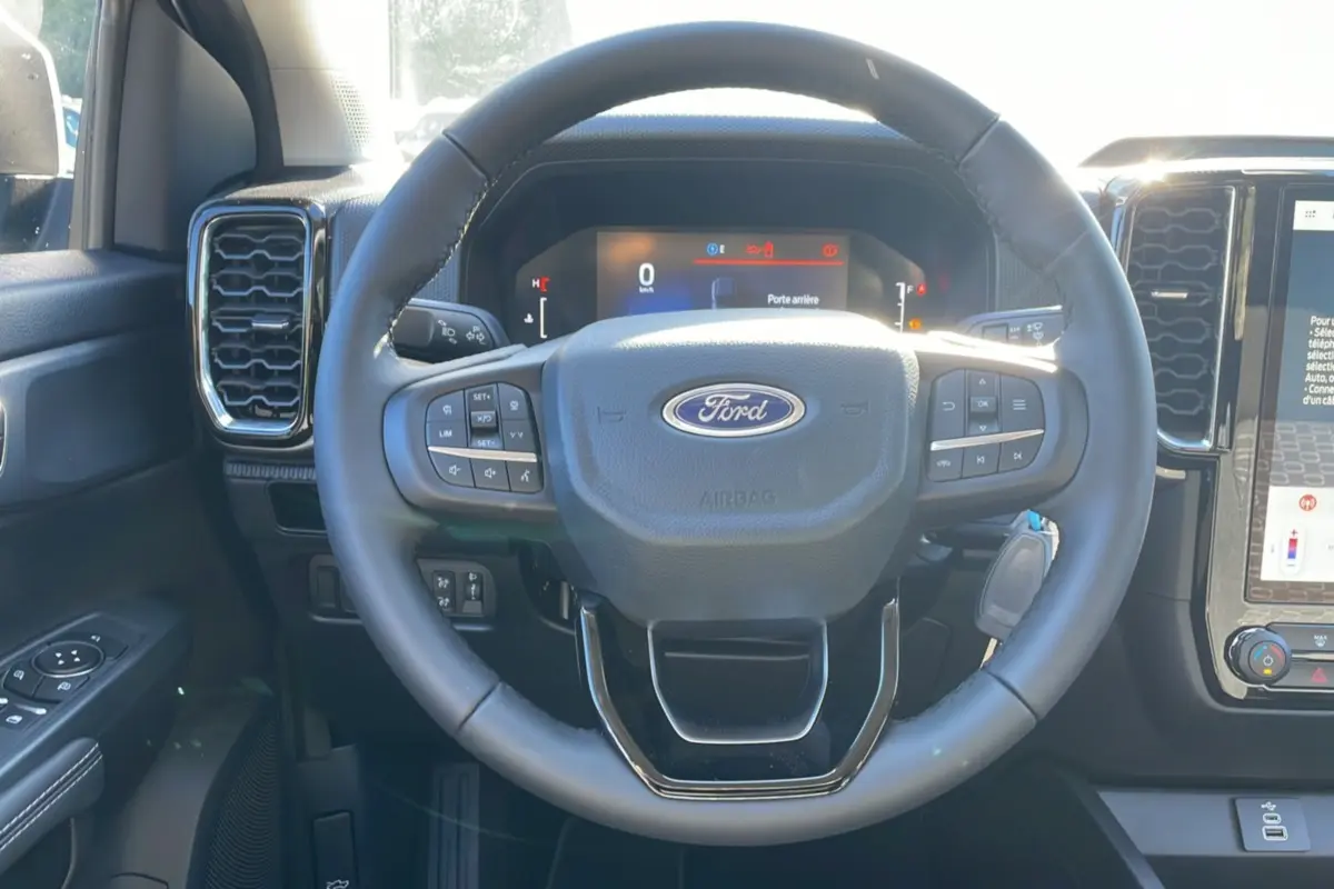Vue intérieure centrée sur le volant cuir multifonctions du Ford Ranger gris iconic avec tableau de bord numérique.