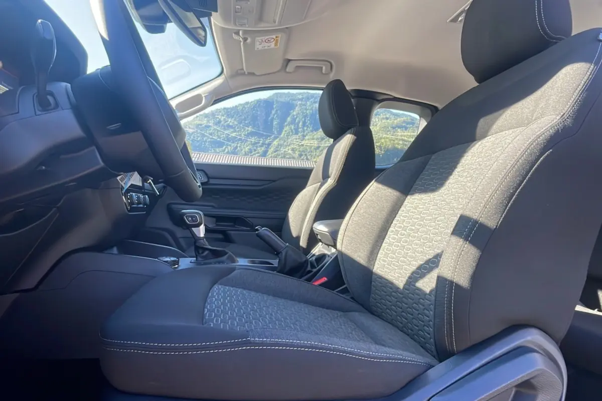 Vue intérieure côté conducteur du Ford Ranger 2026, sièges tissu gris avec surpiqûres blanches et volant multifonctions.
