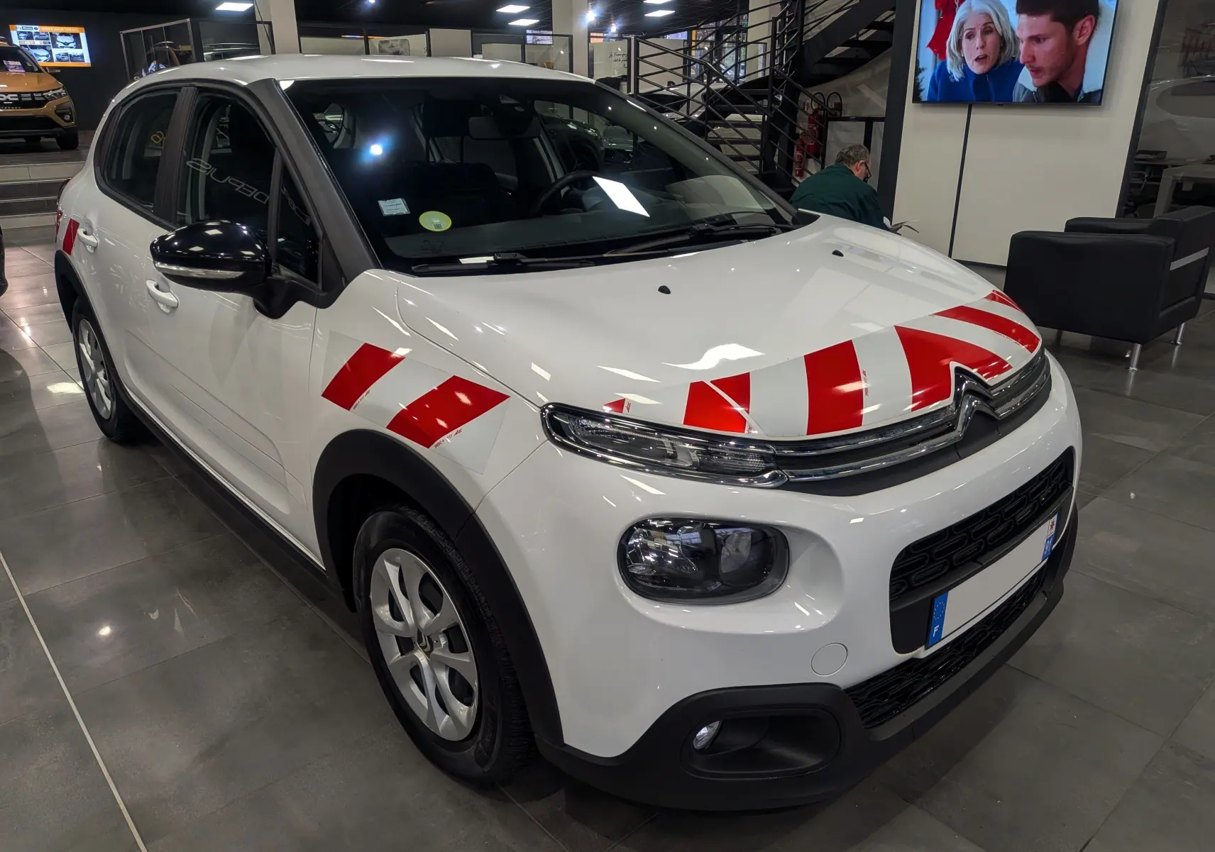 Citroën C3 Société blanc banquise vue 3/4 avant droit avec bandes rouges de signalisation sur capot et aile.