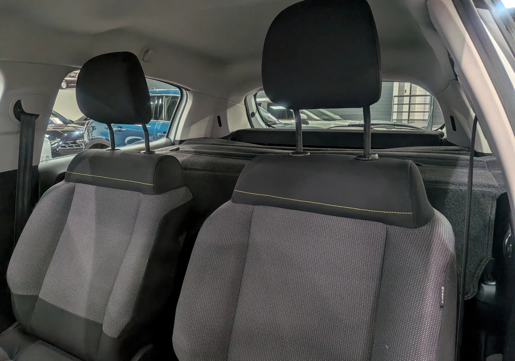 Vue intérieure montrant les sièges avant en tissu gris et noir avec surpiqûres jaunes d'une Citroën C3 Société blanc banquise.