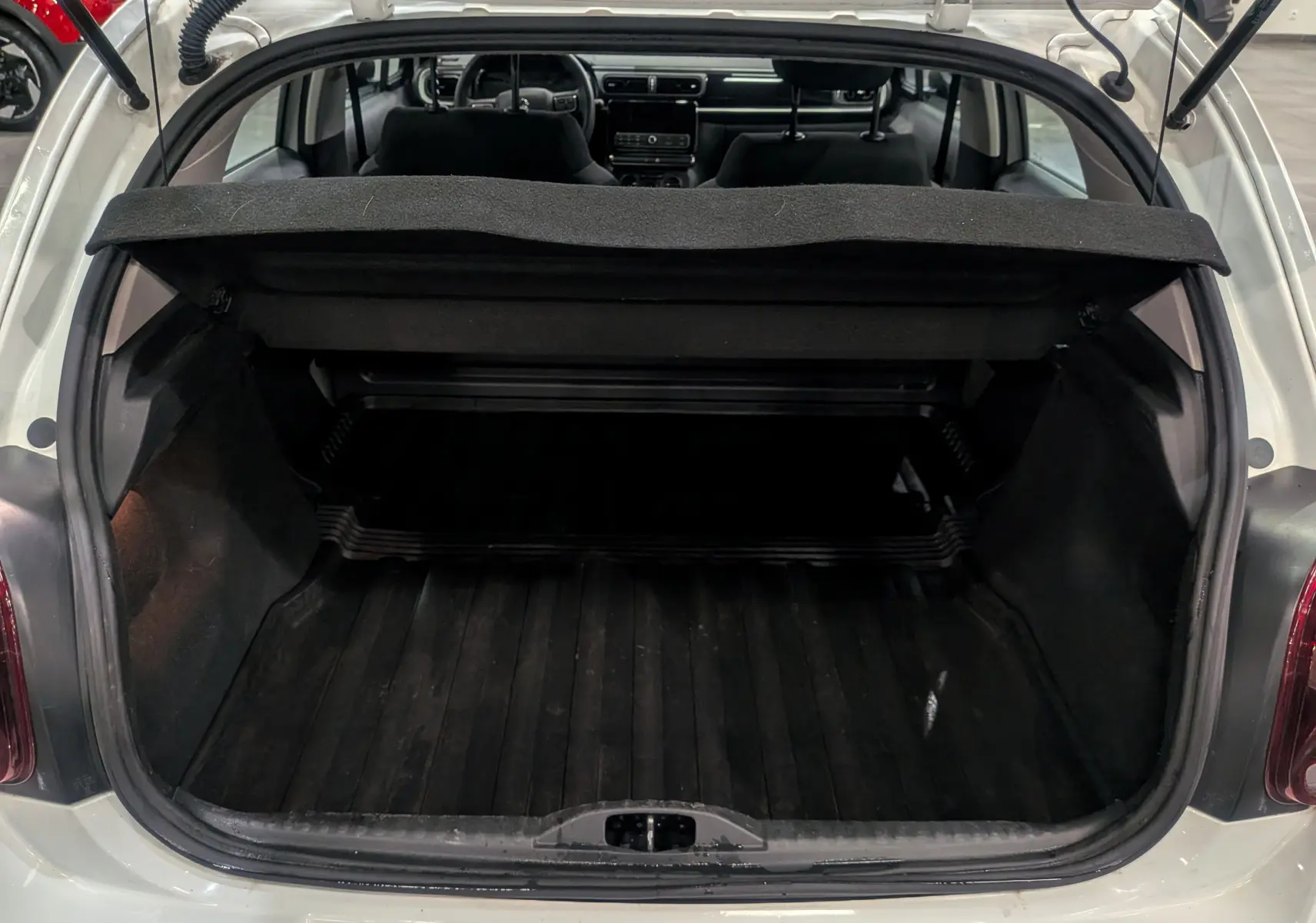 Coffre ouvert vu de l'arrière d'une Citroën C3 Société Blanc Banquise, montrant l'espace de chargement vide et la plage arrière relevée.