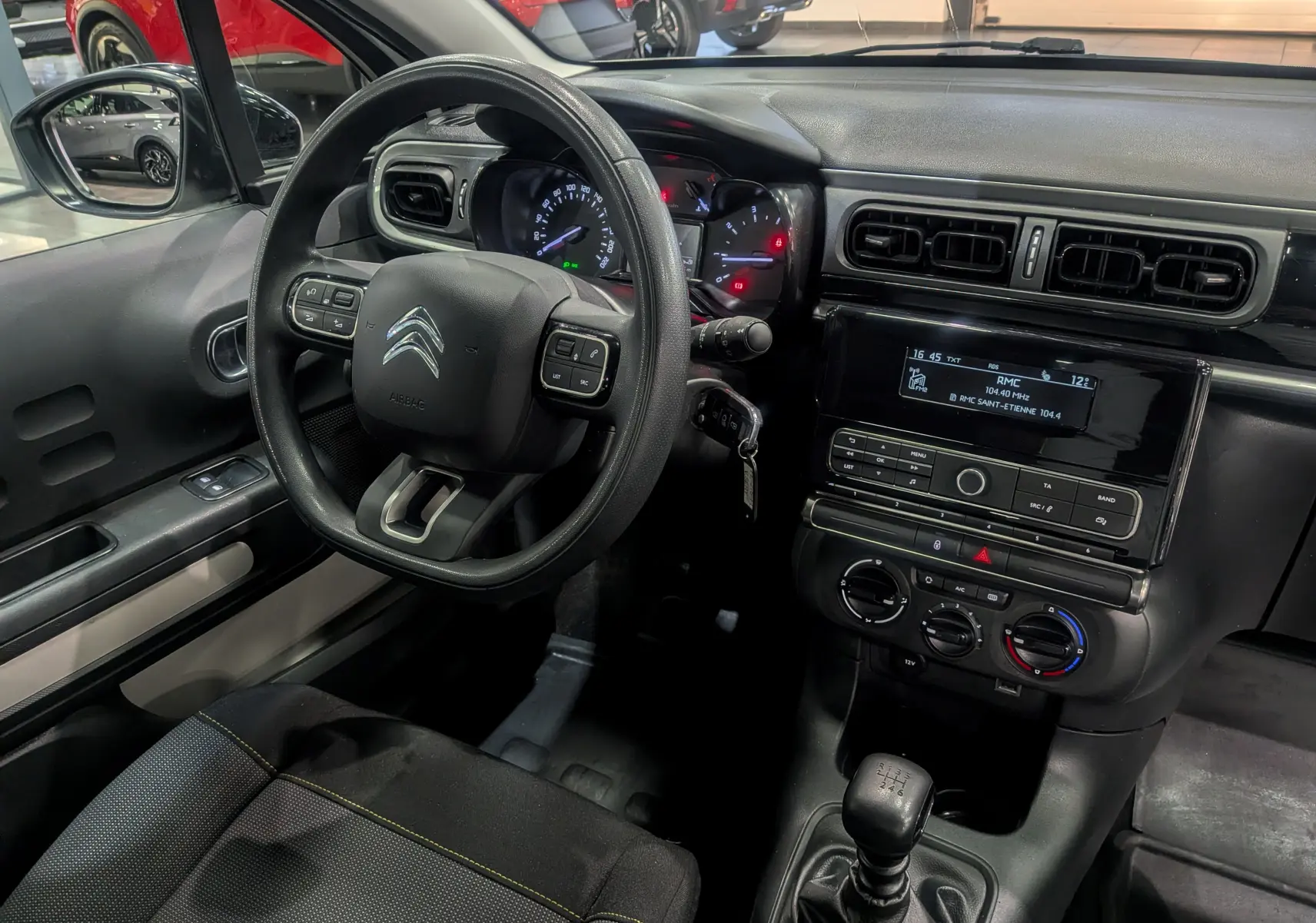Intérieur de la Citroën C3 Société 2019 vu côté conducteur, tableau de bord noir avec commandes et volant multifonction.