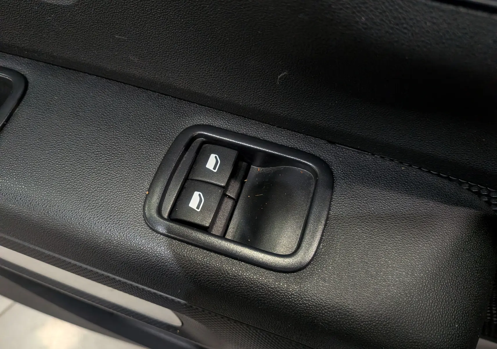 Gros plan sur les commandes de lève-vitres électriques côté conducteur d'une Citroën C3 Société blanc banquise.