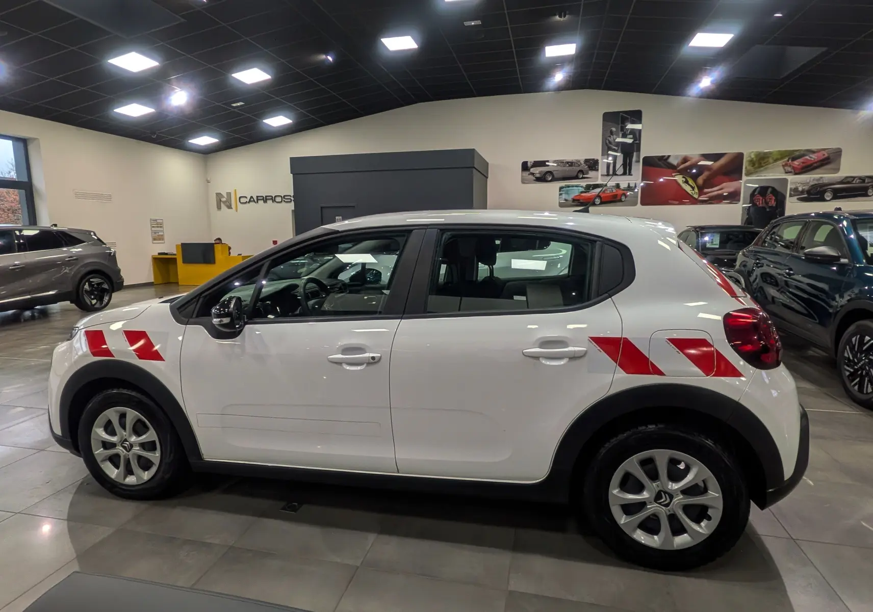 Profil côté gauche d'une Citroën C3 Société blanc banquise avec bandes rouges distinctives sur ailes avant et arrière.