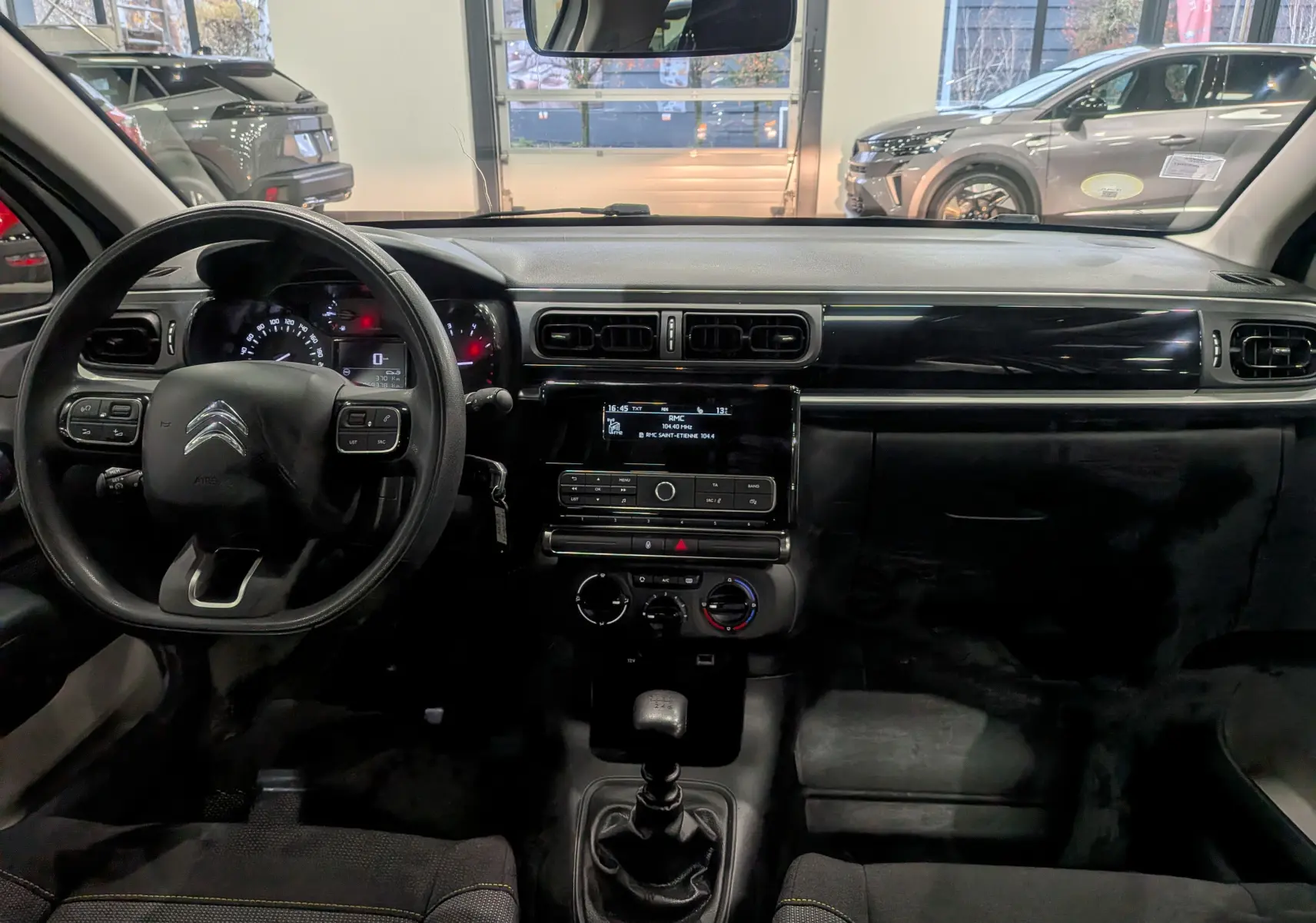 Tableau de bord et volant noir de la Citroën C3 Société BlueHDi 100 vue de face, intérieur tissu et console centrale moderne.