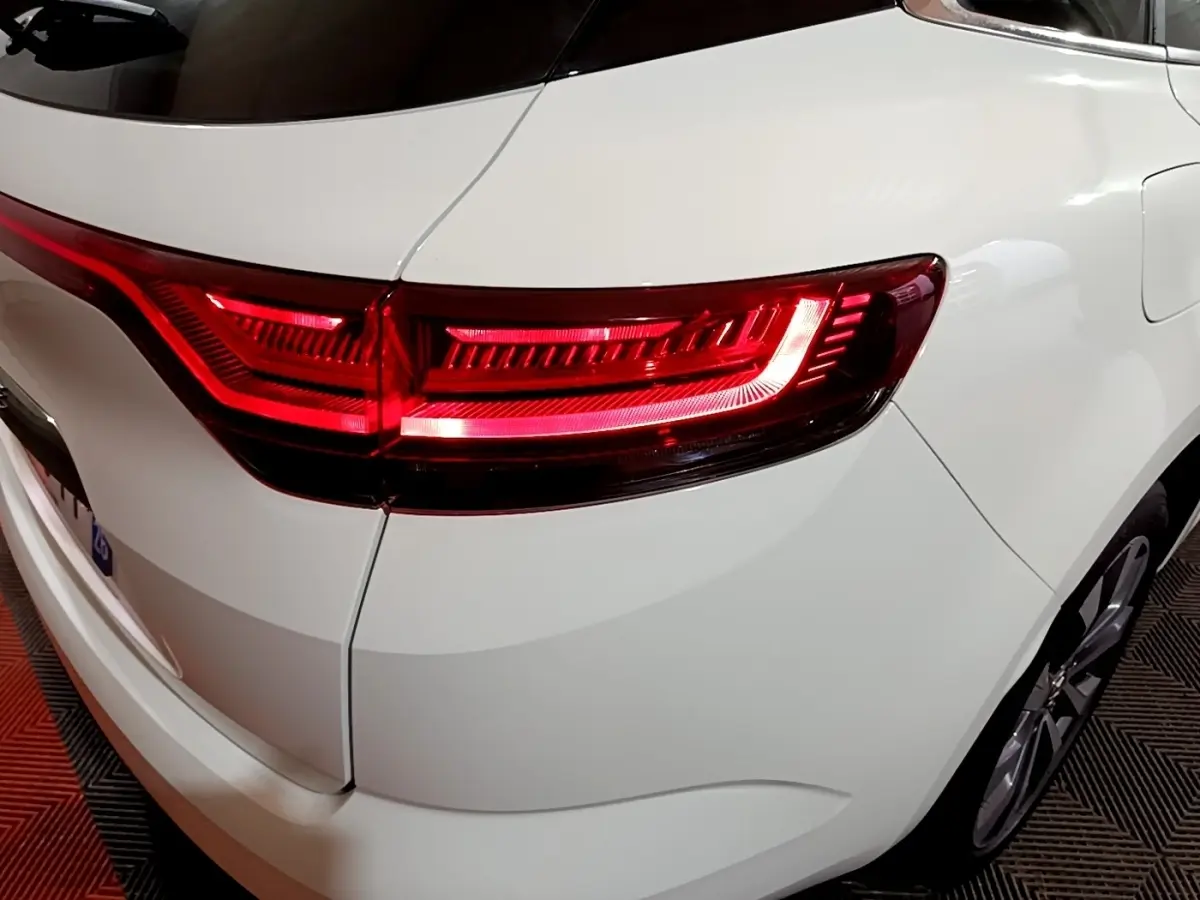 Gros plan sur le feu arrière droit rouge d'une Renault Mégane blanche, vue arrière en intérieur.