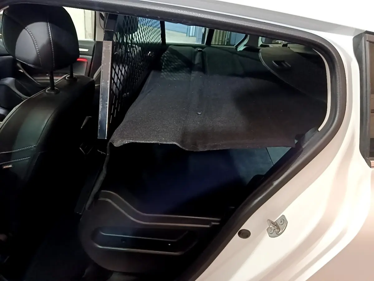 Vue intérieure côté droit du coffre de la Renault Mégane Techno TCe 140 blanc avec banquette rabattue et séparation métallique.