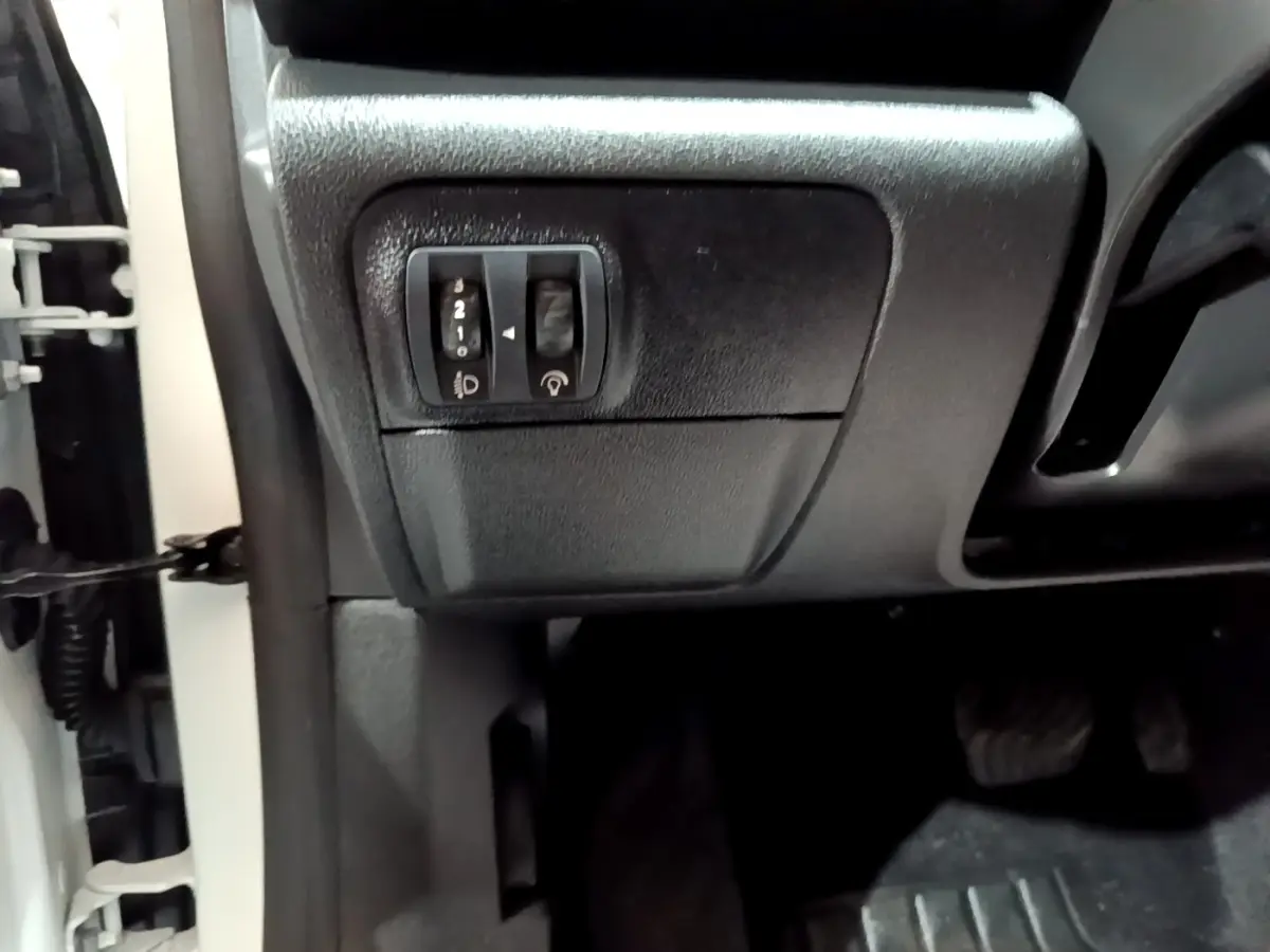 Détail des commandes d’éclairage et réglage sonore côté gauche sous le tableau de bord d’une Renault Mégane blanche.